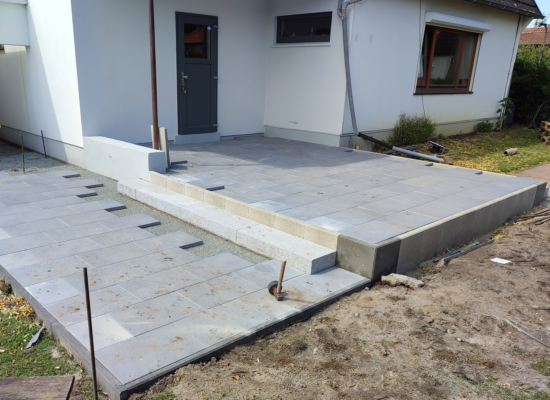Terrassenbau mit großformatigen Terrassenplatten und Granitstufe am Haus